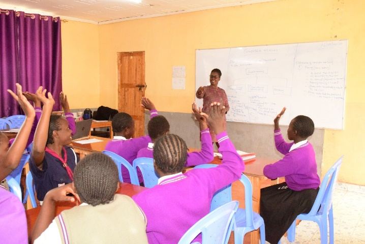 A lesson in progress with learners raising their hands