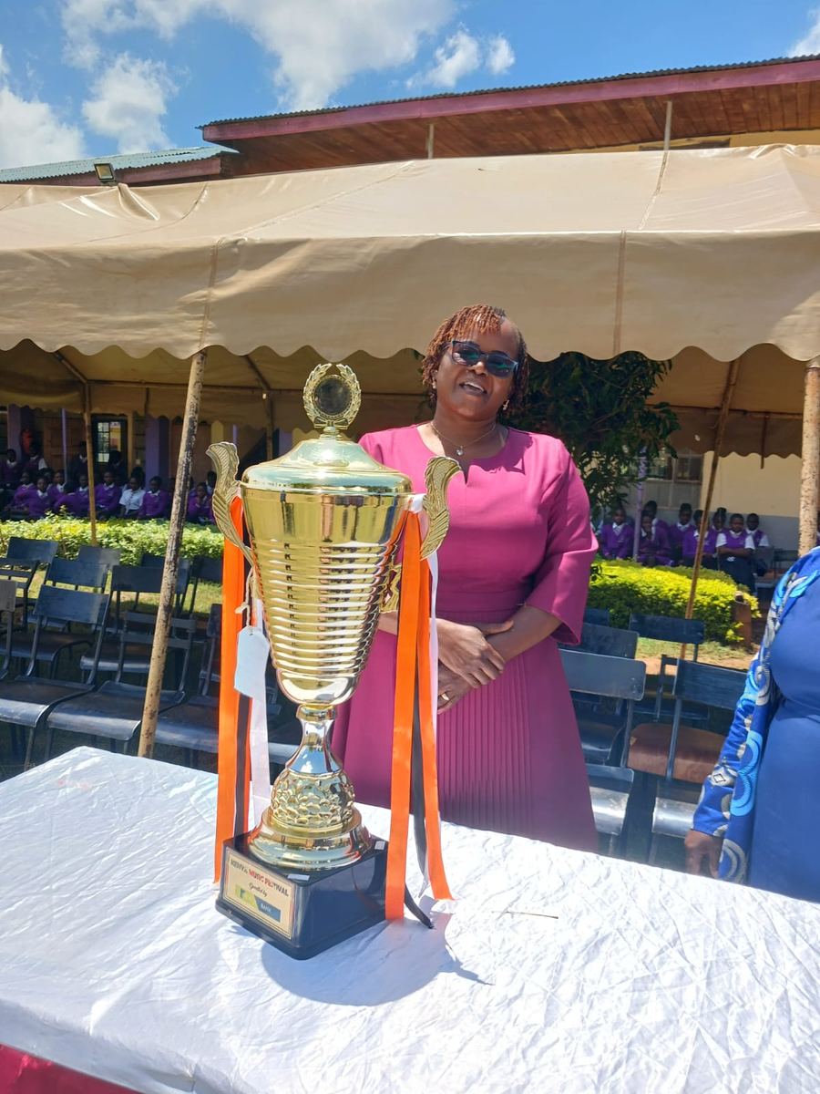 A school leader smiling behind the trophy